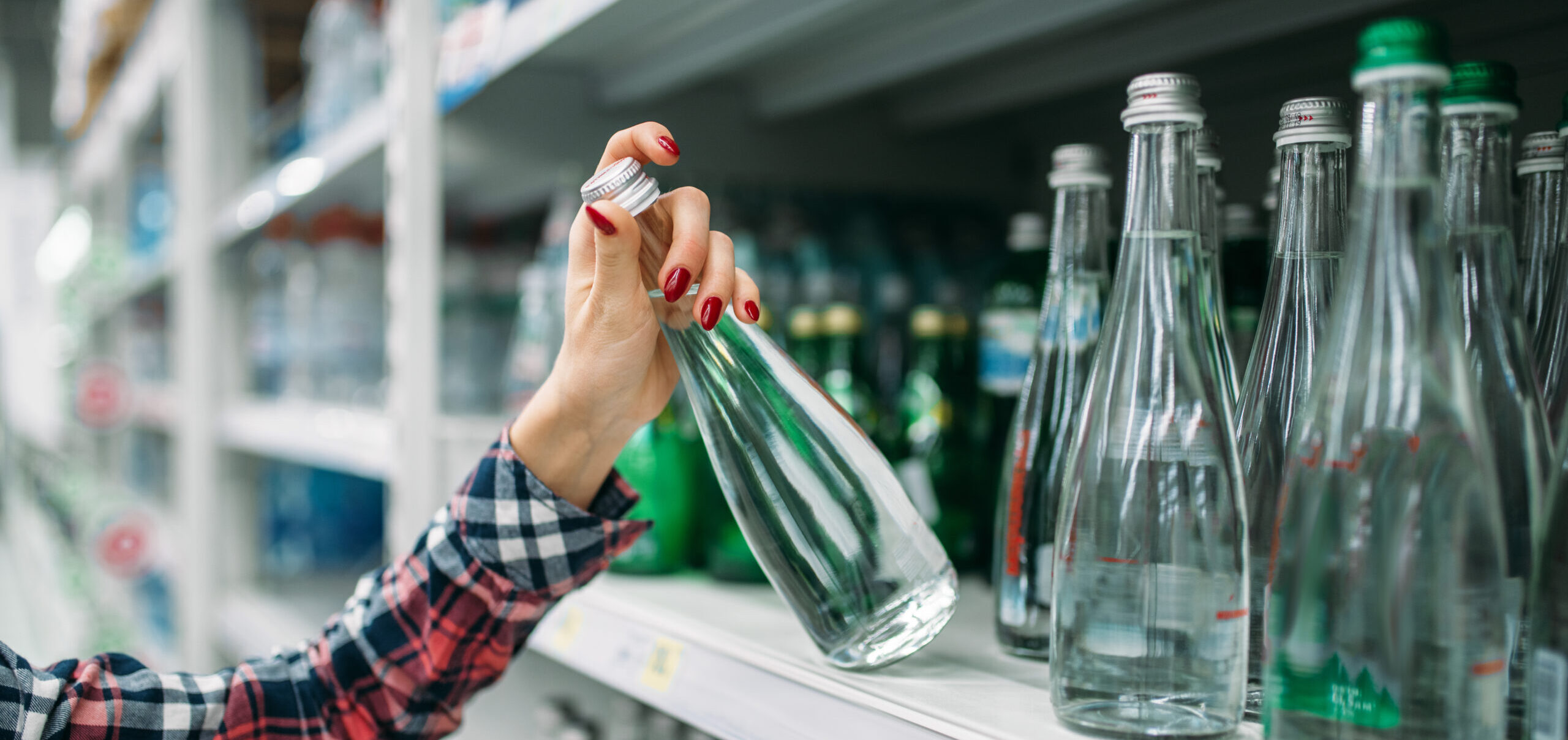 Young woman buying mineral water in supermarket Trinkwasser