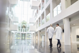 Rückansicht von Ärzten, die sich unterhalten, während sie durch das Krankenhaus gehen